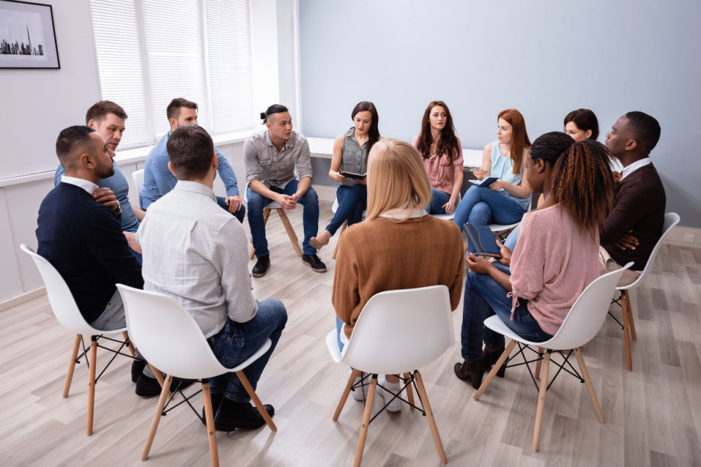 patients sitting in group discussing what is php therapy vs iop|man discussing with his therapist what is php therapy vs iop|woman embracing another woman after choosing between what is php therapy vs iop