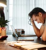 Man,Stressed,While,Working,On,Laptop Acute Stress Disorder vs. PTSD: What’s the Difference?