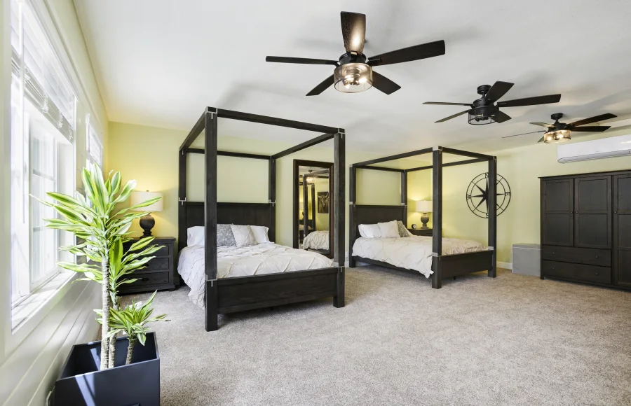 Two canopy beds and garden-facing windows in a shared residential cottage bedroom