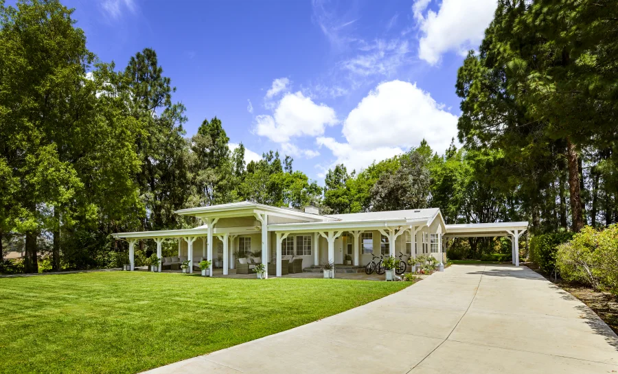 Angled view of the complete residential cottage with covered porch, lawn and approach