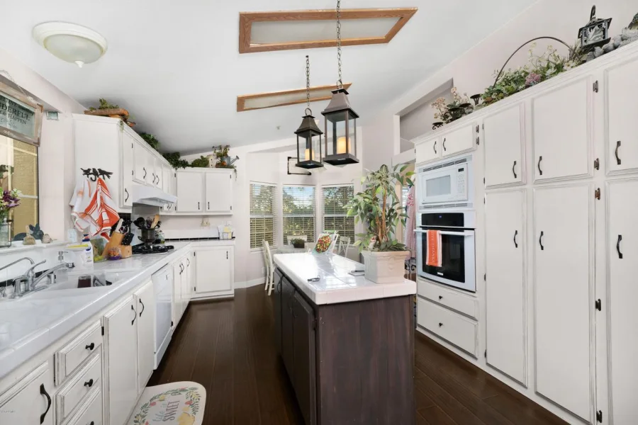Residential cottage kitchen with central island, white cabinetry and skylights