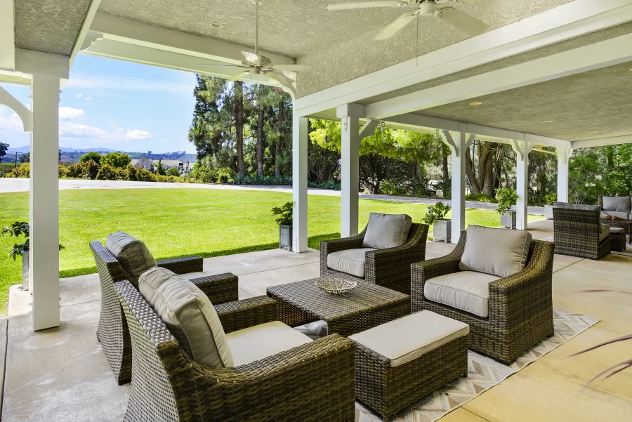 Covered porch seating overlooking the lawn and trees at The Meadowglade residential cottage
