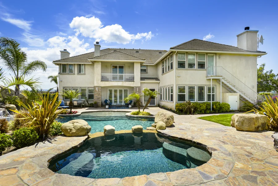 Complete rear exterior of The Meadowglade main house with pool and stone terrace, part of optional supportive housing