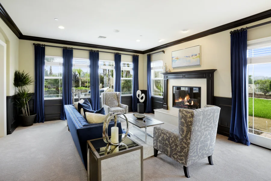 Main-house living room with fireplace, blue seating and garden-facing windows, part of optional supportive housing