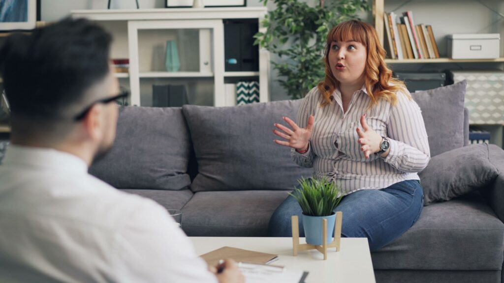 A client talks with a therapist on a grey sofa