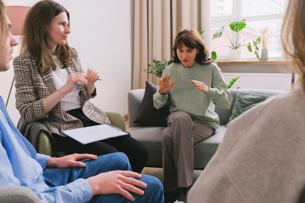 A therapist leads a small group therapy session in a bright living room