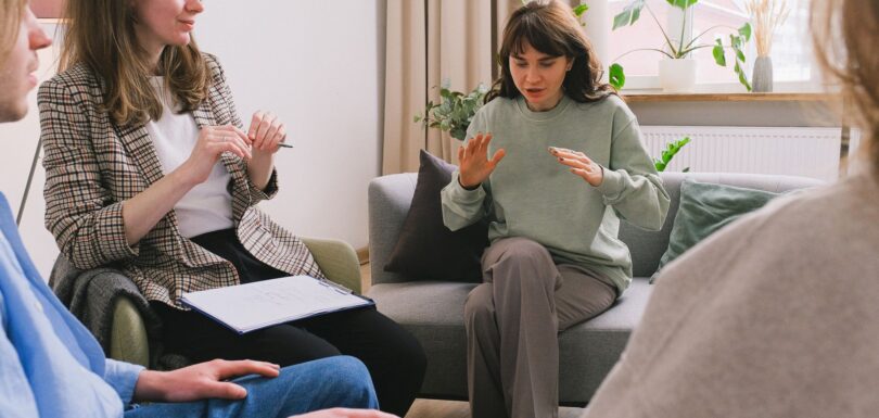 A therapist leads a small group therapy session in a bright living room